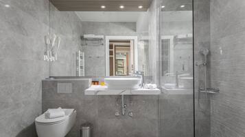 Un baño moderno con ducha envuelta en vidrio, un lavamanos blanco y un inodoro.