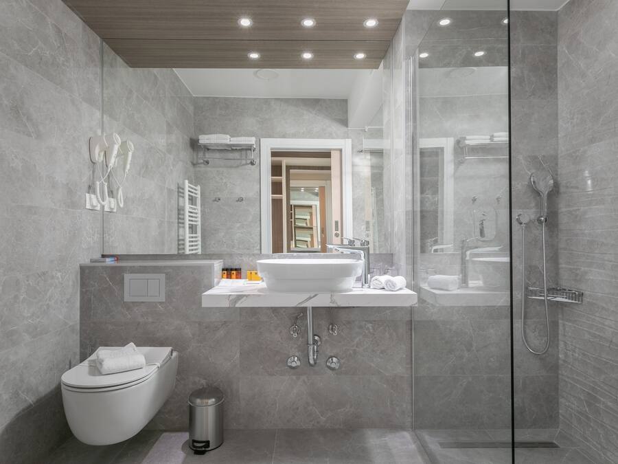 A modern bathroom with a glass-enclosed shower, a white sink, and a toilet.