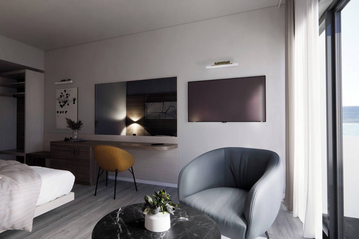 Un dormitorio moderno con una cama, un escritorio, una silla y un ventanal grande.
