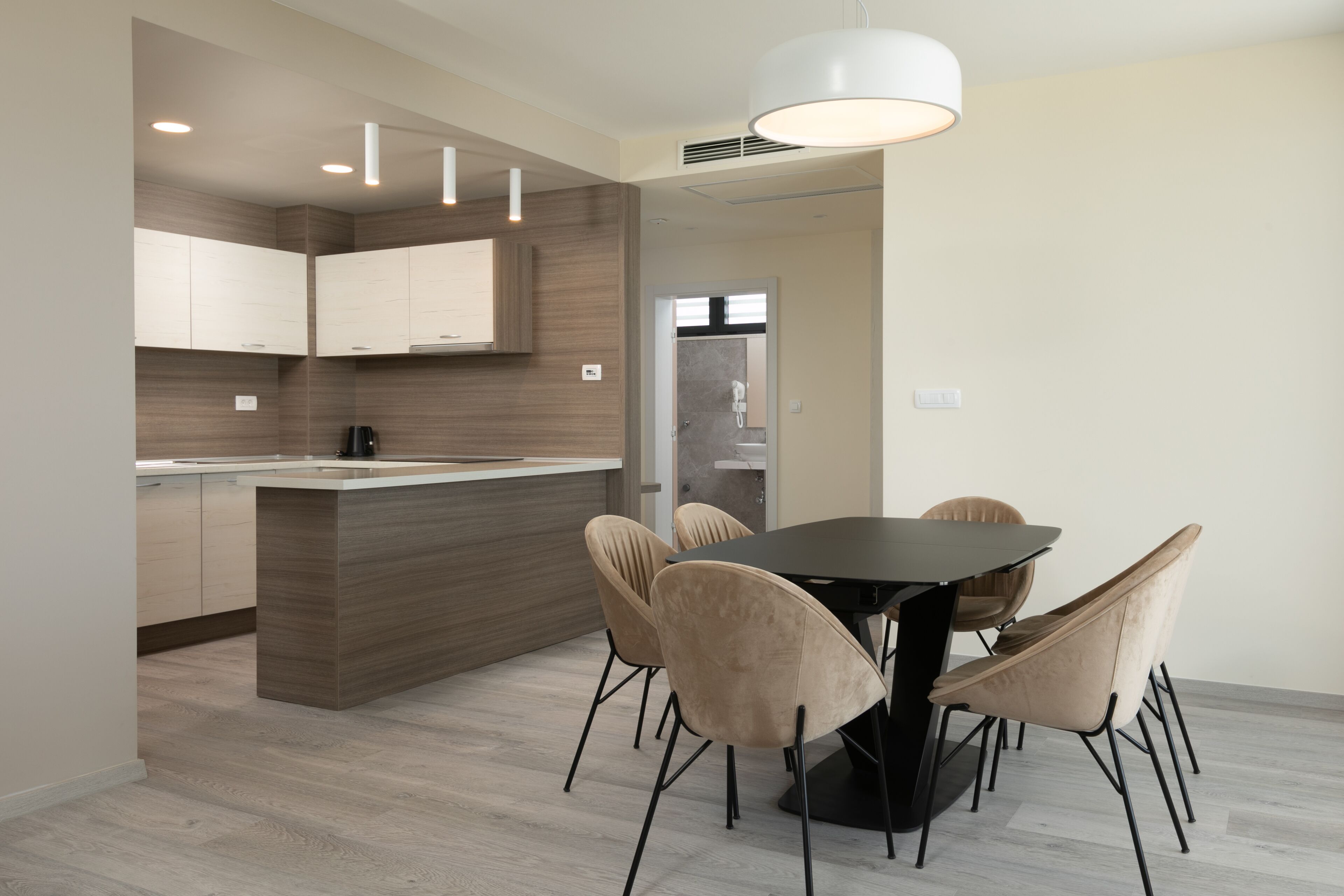 A modern kitchen with a central island, beige chairs, and a dining table.
