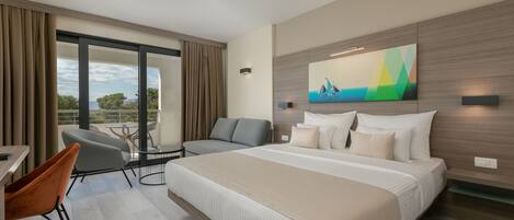 A modern hotel room with a large bed, a seating area with a table, and a view of the outdoors.