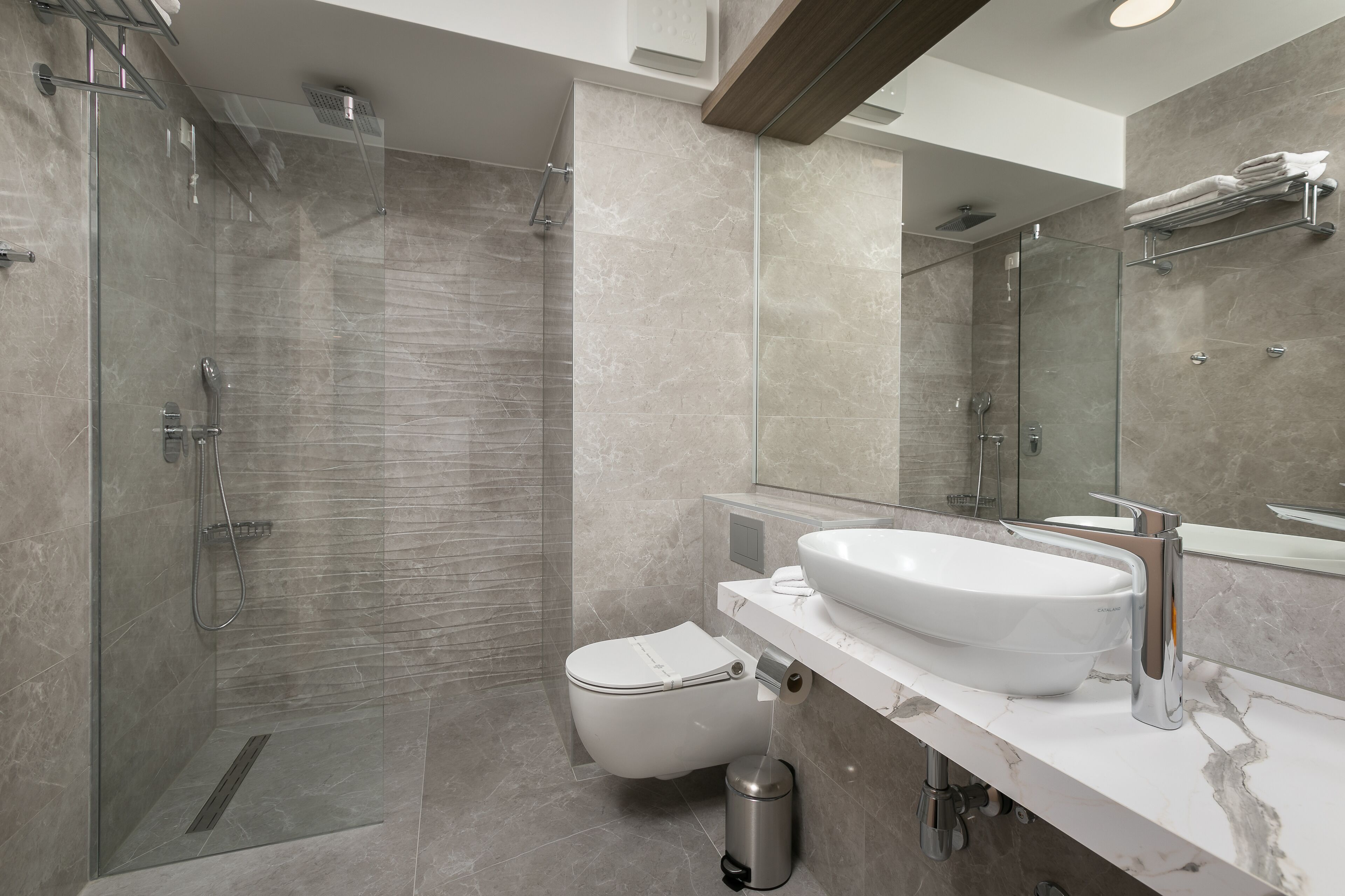 Une salle de bain moderne avec une douche à parois de verre, un lavabo blanc et des toilettes.