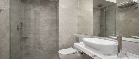 Une salle de bain moderne avec une douche à parois de verre, un lavabo blanc et des toilettes.