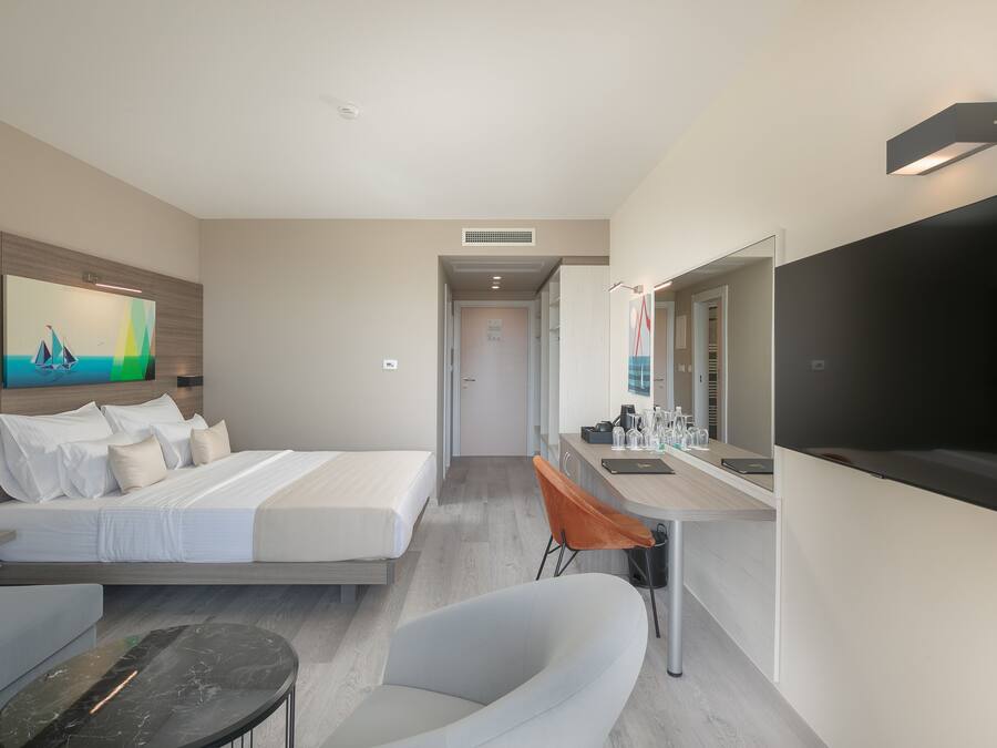 Una habitación de hotel moderna con una cama, un sofá, un escritorio con espejo y un televisor.