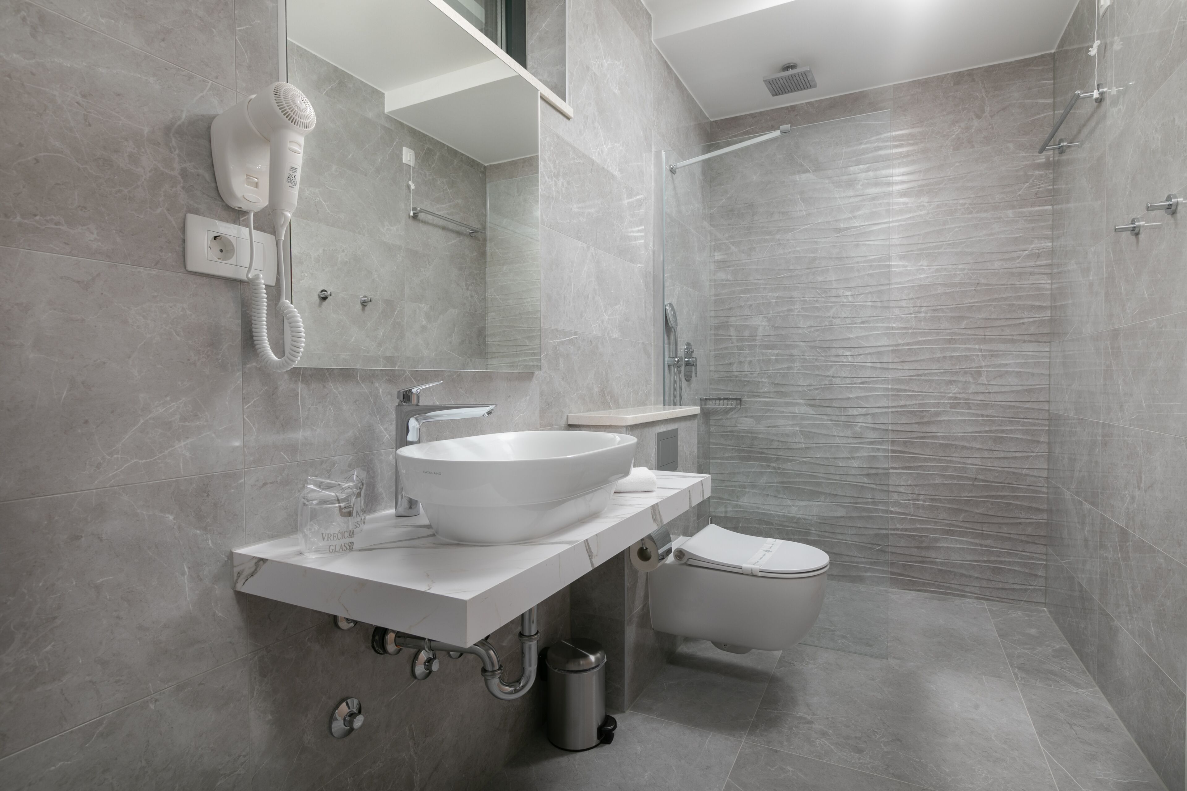 Une salle de bain moderne avec un lavabo, un miroir et des toilettes, le tout de couleur blanche.