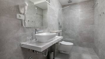 Une salle de bain moderne avec un lavabo, un miroir et des toilettes, le tout de couleur blanche.