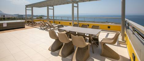 A rooftop terrace with a table and chairs, a pergola, and a view of the sea.