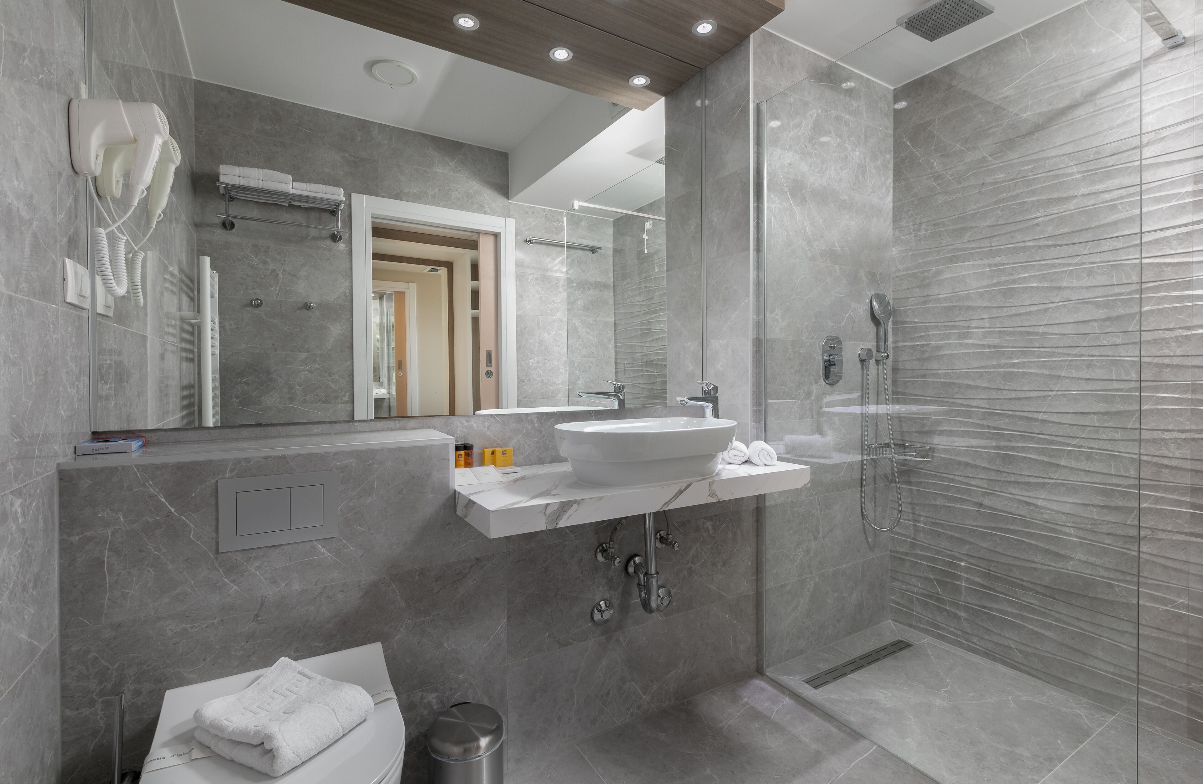Un bagno moderno con un grande specchio, un lavabo integrato e una cabina doccia in vetro.
