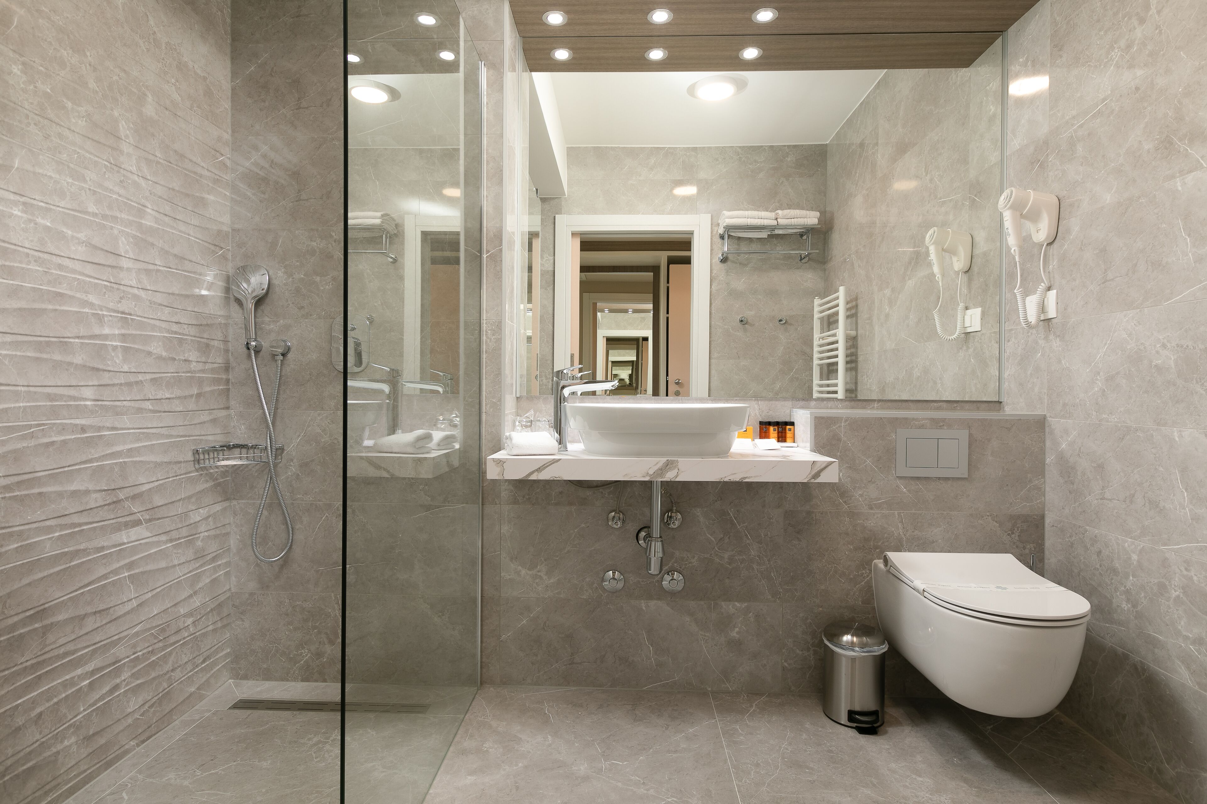 Ein modernes Badezimmer mit einer Duschkabine aus Glas, einem weißen Waschbecken und einer Toilette.