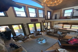 Amplia sala de estar con chimenea, ventanas grandes y un techo alto.