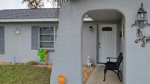 A house with a white exterior, a front door, a bench, and a butterfly decoration. - Florida escape Quiet area.Restaurants all over,Clearwater 1 hr away,Orlando1hr.  (Spring Hill)