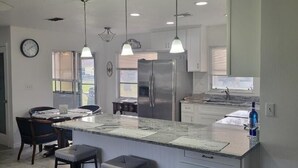 A modern kitchen with a central island, pendant lights, and stainless steel appliances. - Florida escape Quiet area.Restaurants all over,Clearwater 1 hr away,Orlando1hr.  (Spring Hill)
