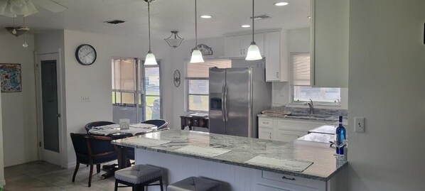 A modern kitchen with a central island, pendant lights, and stainless steel appliances.