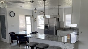 A modern kitchen with a central island, bar stools, and a refrigerator. - Florida escape Quiet area.Restaurants all over,Clearwater 1 hr away,Orlando1hr.  (Spring Hill)