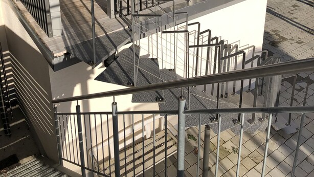 Une terrasse sur le toit, avec une table et des chaises, une rambarde et une vue sur le paysage urbain.