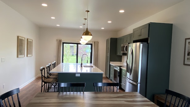 Una cocina moderna con una isla central, armarios oscuros y un refrigerador de acero inoxidable.