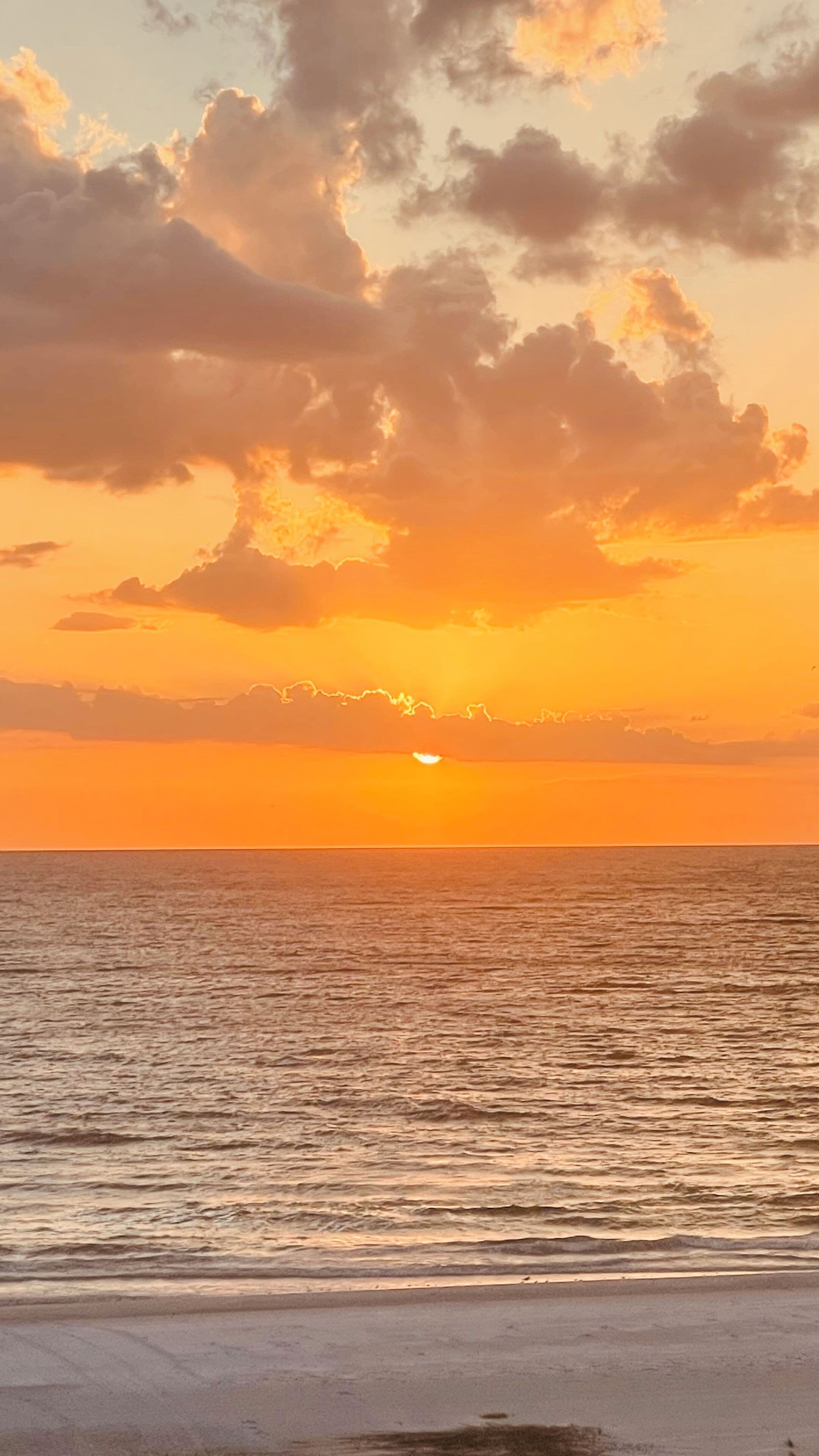 A sunset over the ocean with clouds in the sky.