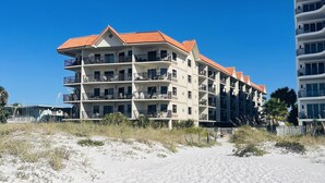 A beachfront hotel with multiple balconies and a red-tiled roof.