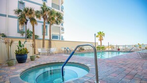 A swimming pool with a pool ladder, surrounded by palm trees and lounge chairs.