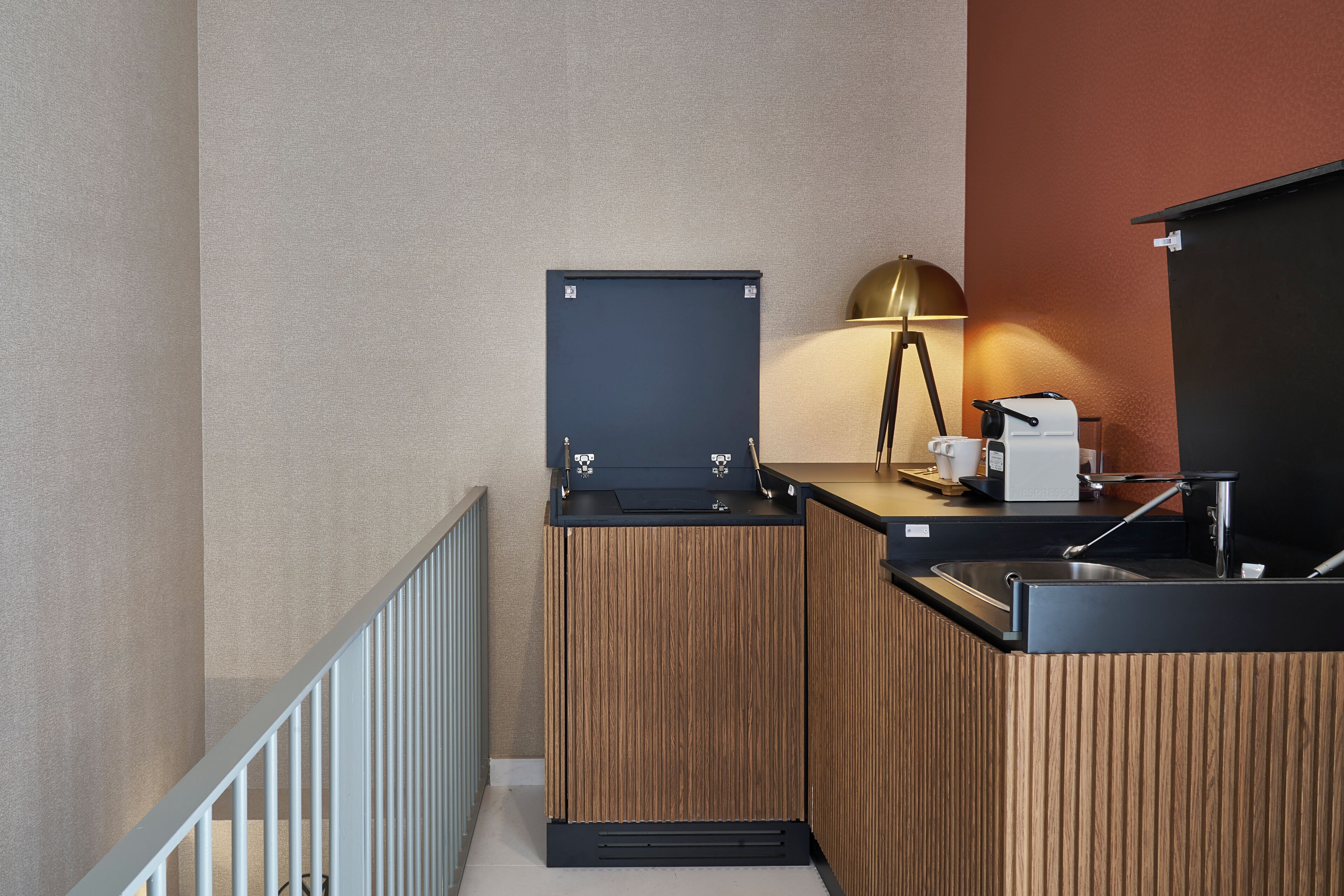 Una kitchenette compacta con cafetera, pileta y un mueble pequeño.