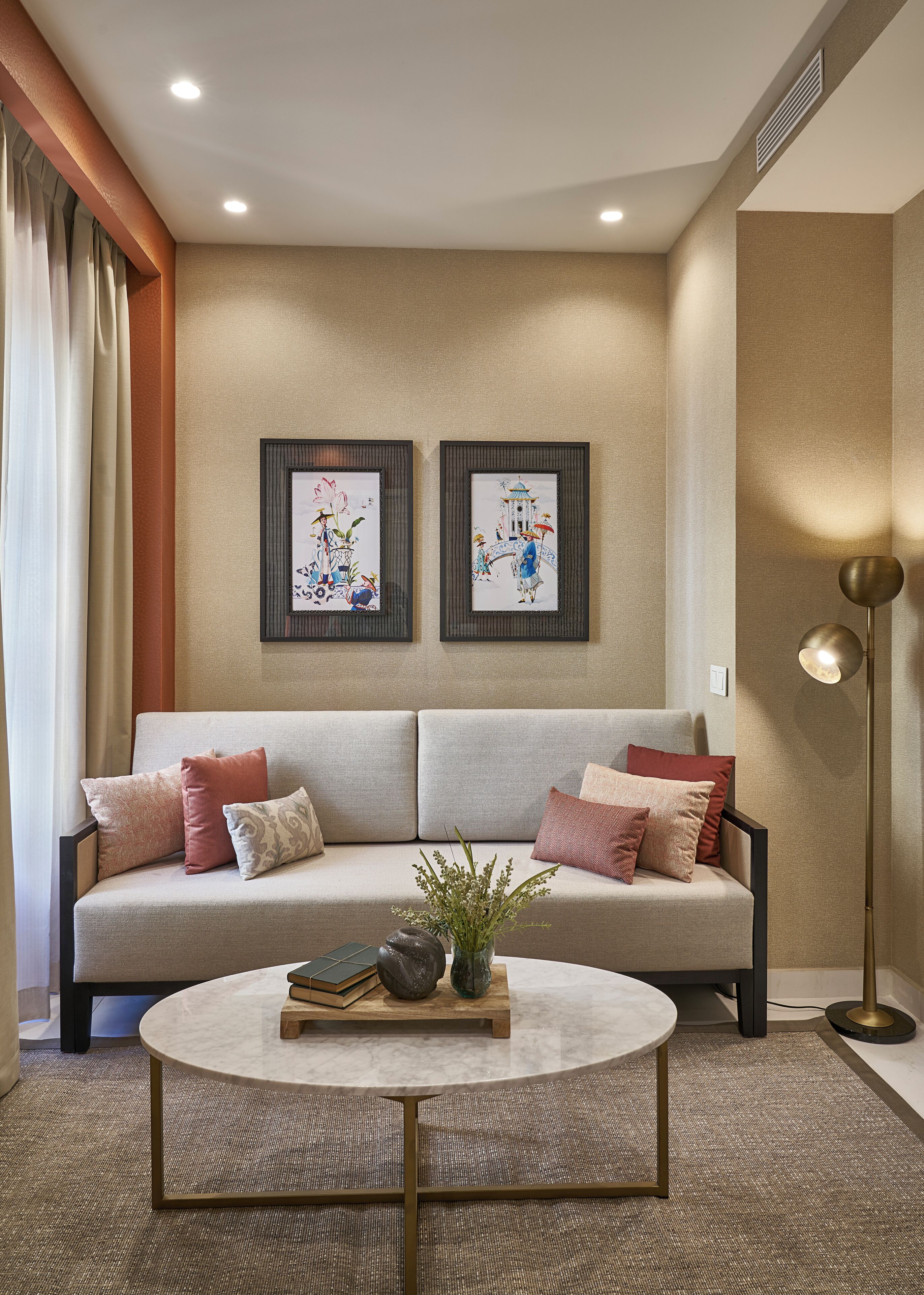 A modern living room with a sofa, pillows, a coffee table, and two framed artworks on the wall.