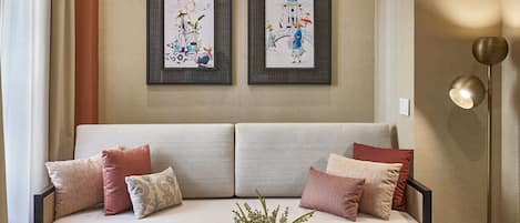 A modern living room with a sofa, pillows, a coffee table, and two framed artworks on the wall.