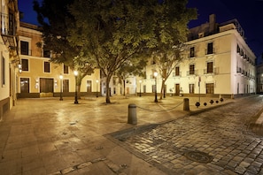 A cobblestone street at night with historic buildings, trees, and street lamps. - Hotel Vincci Molviedro Suites Apartments (Seville)