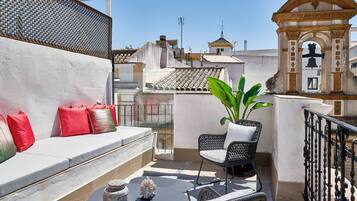 Un balcón con una zona de estar, una planta en maceta y una campana decorativa.