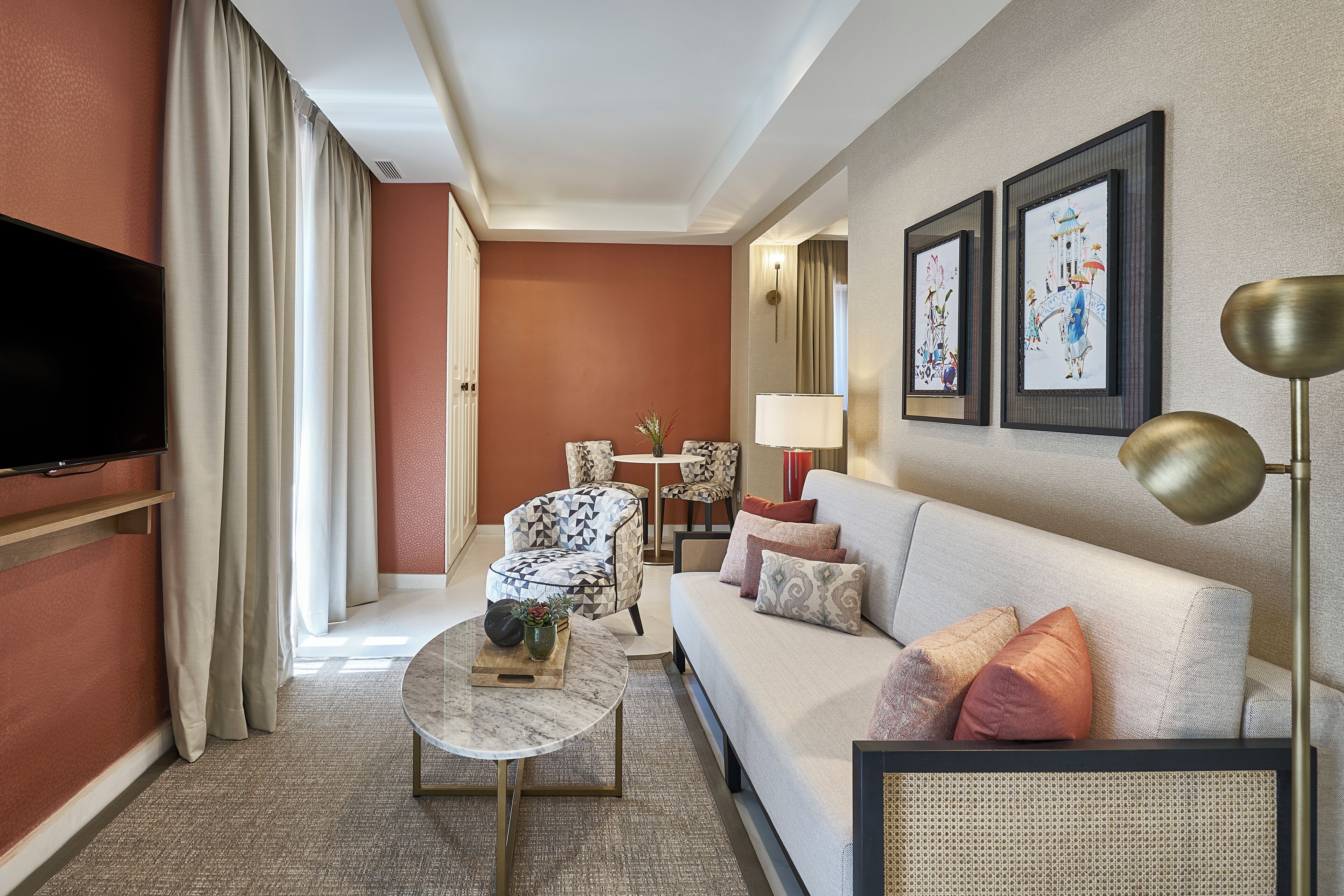 Una sala de estar moderna con un sofá, una mesa de centro, un televisor y un sillón estampado.