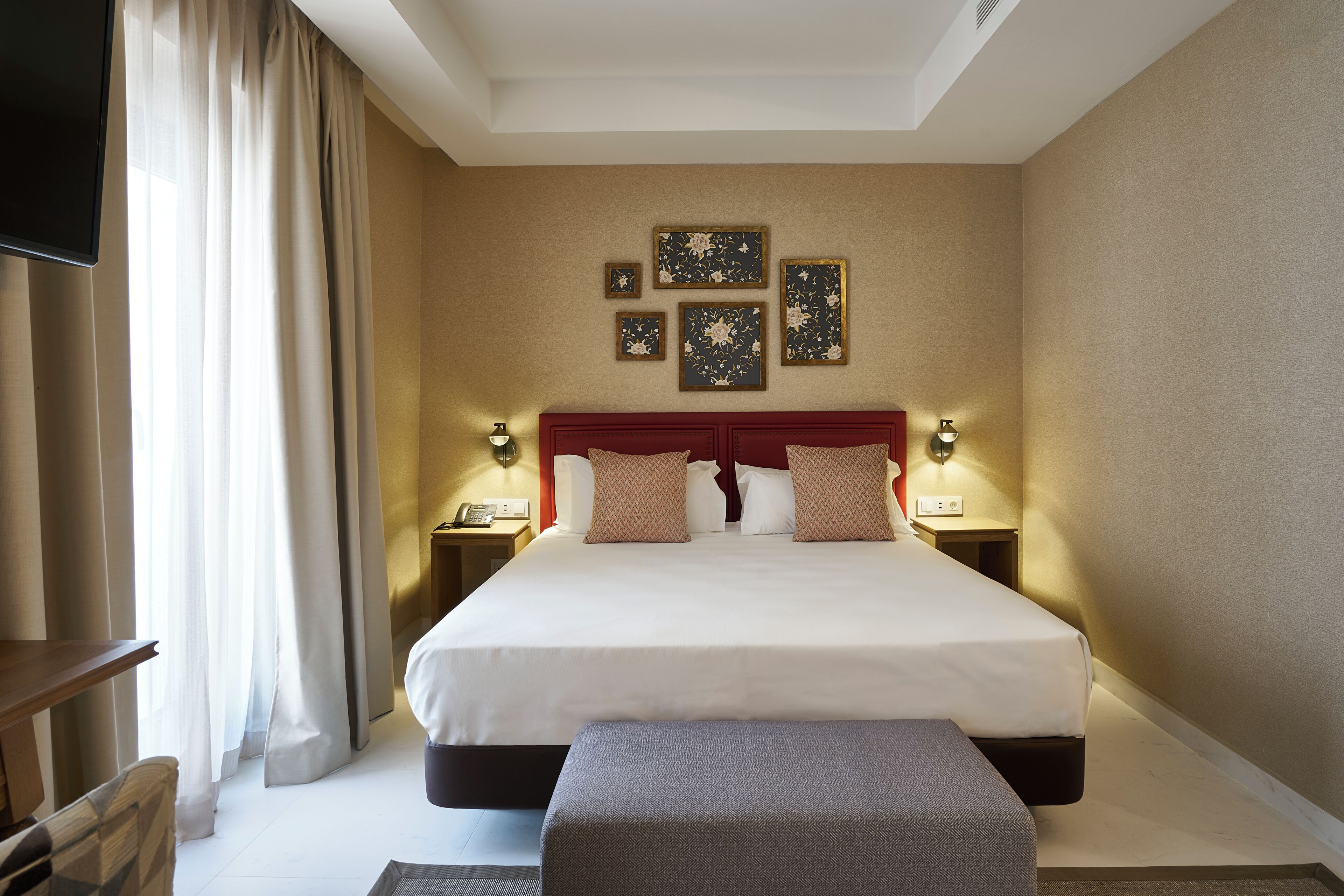 A hotel room with a large bed, bedside lamps, a flat-screen TV, and artwork on the wall.