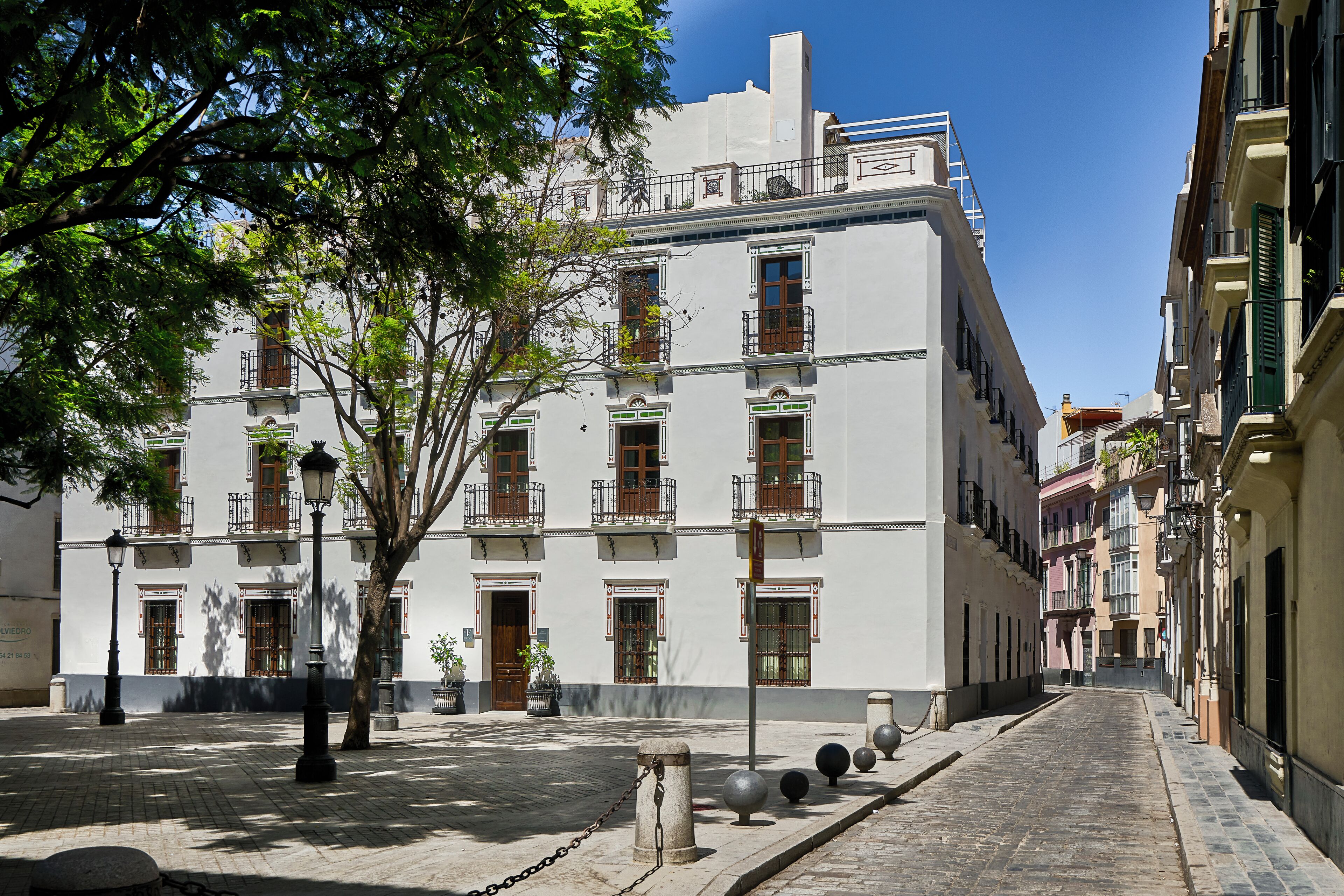 Un edificio con diverse finestre e balconi, un cortile lastricato e un cielo sereno.