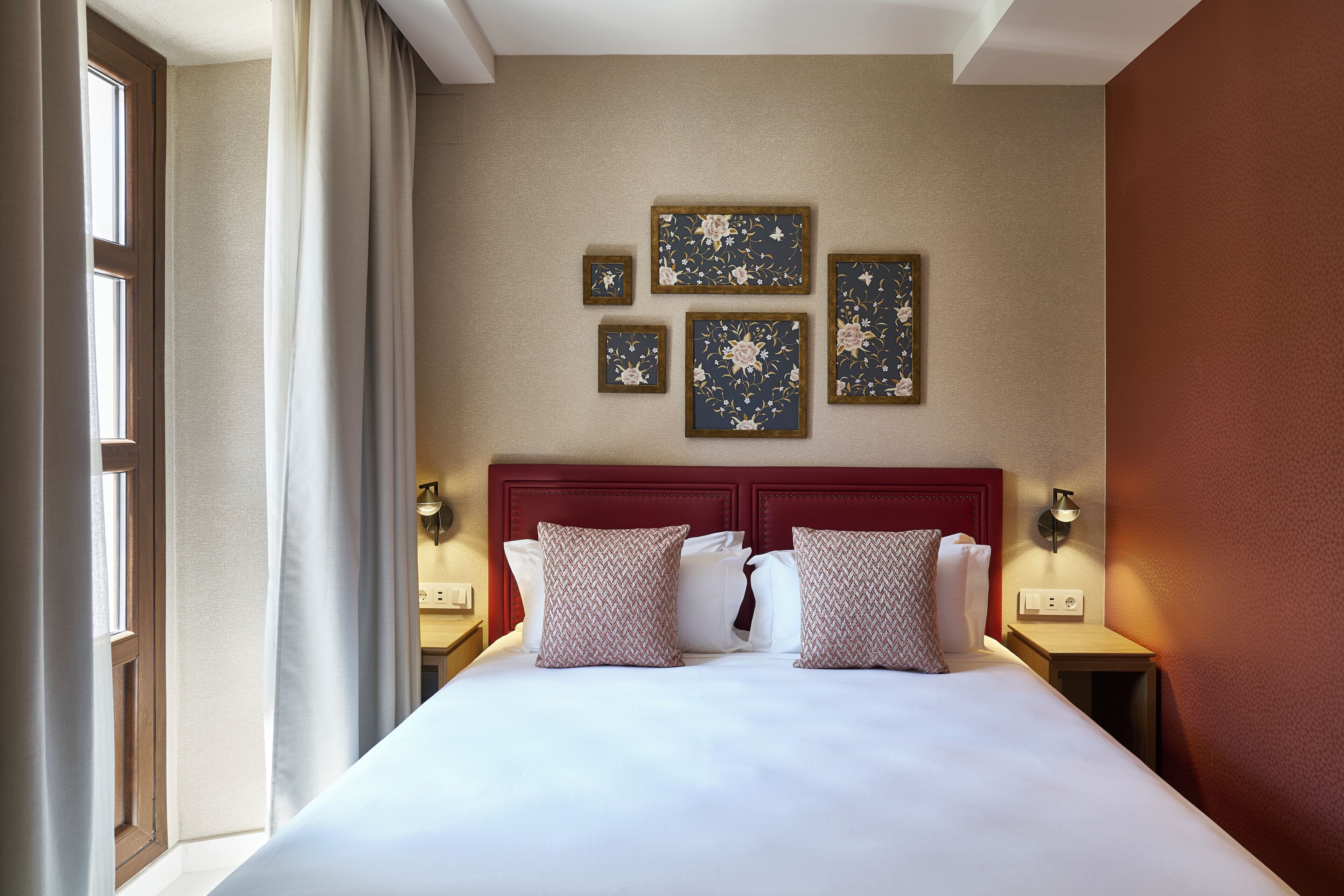 A hotel room with a large bed, multiple pillows, wall-mounted artwork, and bedside lamps.