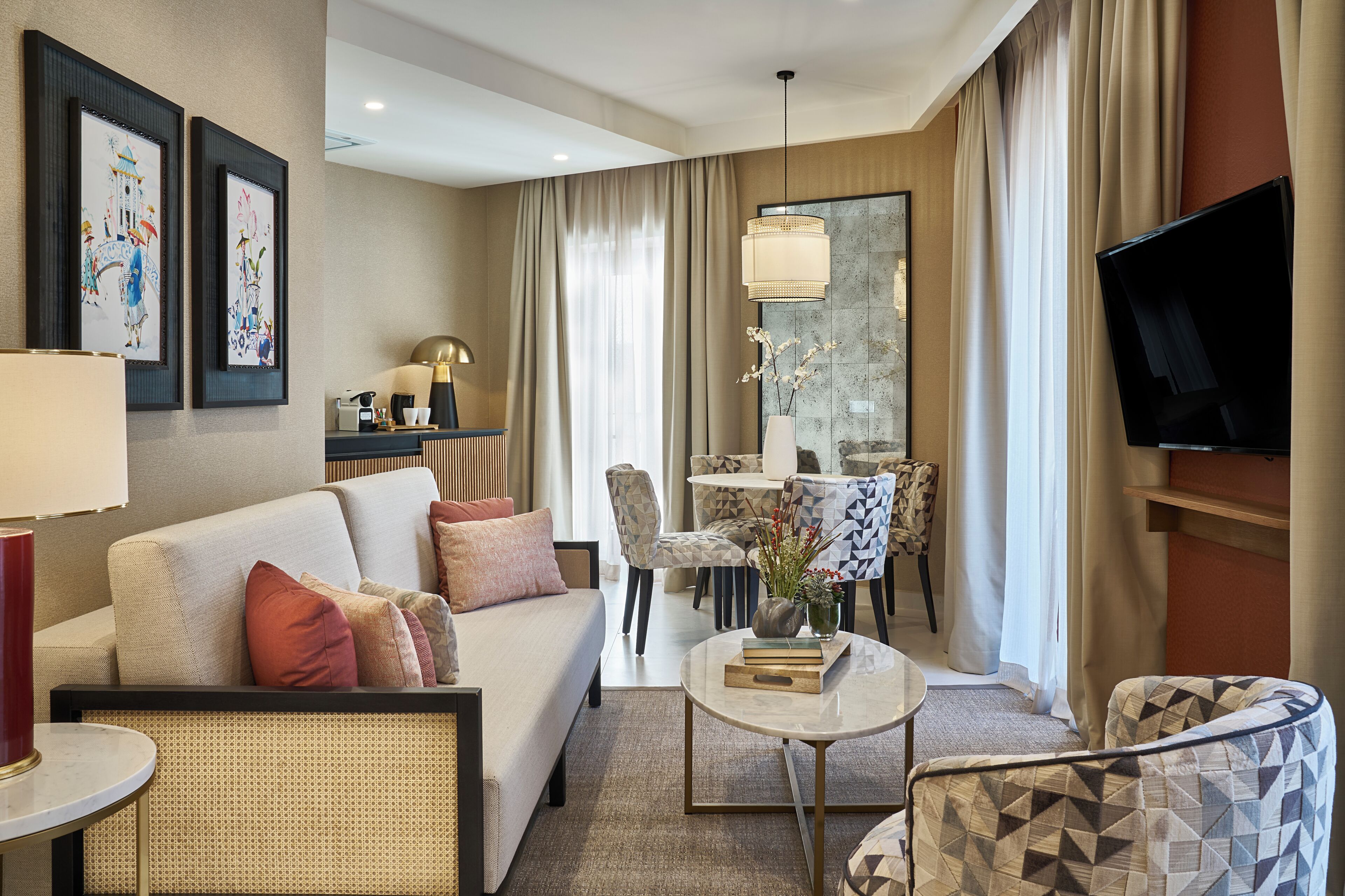 Een moderne hotelkamer met een bank, fauteuils, een salontafel en een televisie.