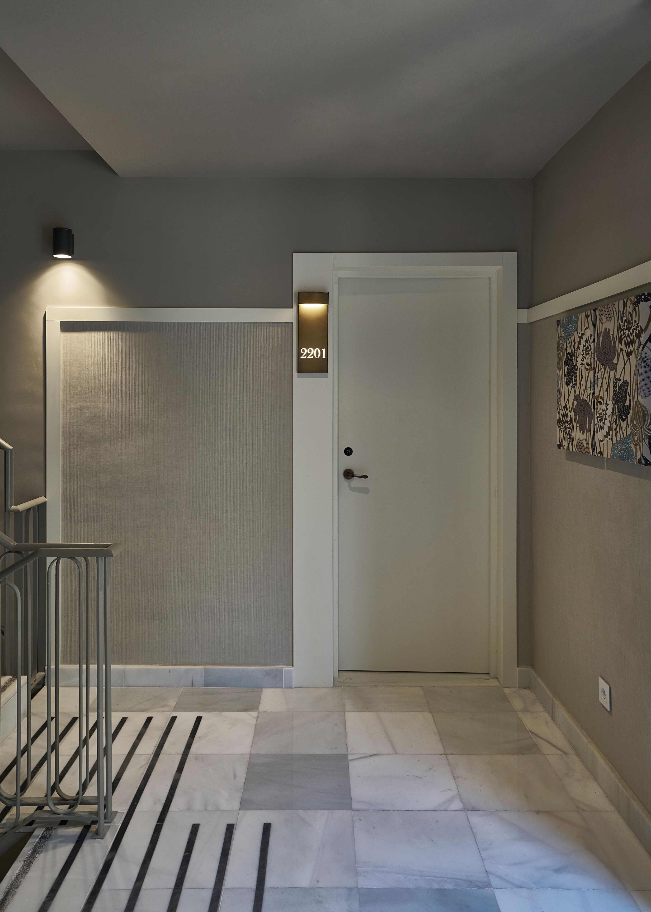 A hallway with a door marked '2201', a metal railing, and a patterned wall decoration.