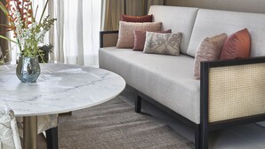 A modern living room with a sofa, a round table, and a vase with flowers.