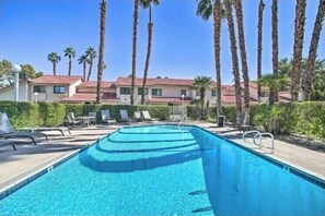 Relax by the pool surrounded by palm trees and lounge chairs.