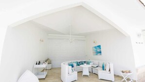 Een witte ruimte met een gebogen witte bank, een ronde witte tafel en een witte poef.