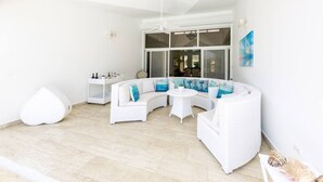 Een moderne, witte woonkamer met een gebogen witte bank, een ronde salontafel en een witte zitkruk.