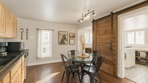 Una cocina moderna con armarios de madera, una mesa de comedor de cristal y una puerta corredera estilo establo.