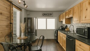 Una cocina moderna con armarios de madera, electrodomésticos de acero inoxidable y una mesa de comedor de vidrio.