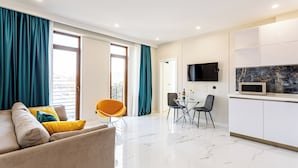Una sala de estar moderna con un sofá, una mesa de comedor y sillas. Hay una zona de cocina con un microondas y armarios.
