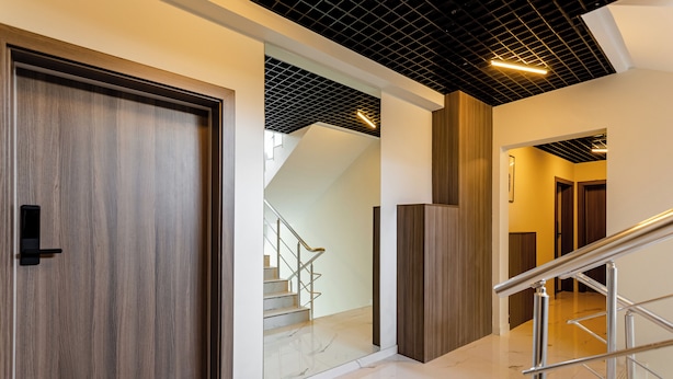 Un interior moderno con una puerta de madera, una escalera y una barandilla de metal.