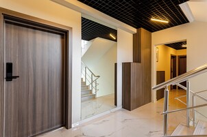 Un interior moderno con una puerta de madera, una escalera y una barandilla de metal.