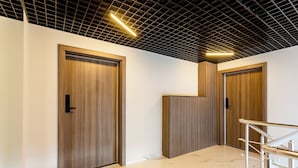 Un interior moderno con dos puertas de madera, suelo de mármol y barandilla metálica.