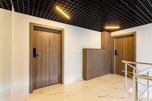 Un interior moderno con dos puertas de madera, suelo de mármol y barandilla metálica.