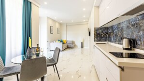 Una cocina moderna con salpicadero de mármol, un comedor con mesa y sillas de vidrio, y una sala de estar con sofá y mesa de centro.