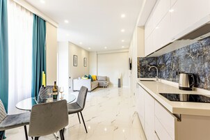 Una cocina moderna con salpicadero de mármol, un comedor con mesa y sillas de vidrio, y una sala de estar con sofá y mesa de centro.