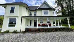 A two-story house with a covered porch and a gravel driveway. - 6BR Cozy Farmhouse Retreat w/ Sunset Views & Fun
Minutes from Train to Seattle (Sumner)