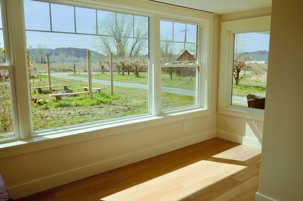 Una habitación con ventanas amplias que ofrecen vistas a un paisaje rural, incluyendo una carretera y árboles.