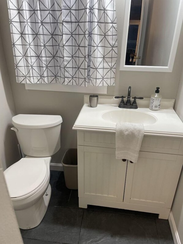 Et badeværelse med toilet, håndvask og et spejl over vasken.